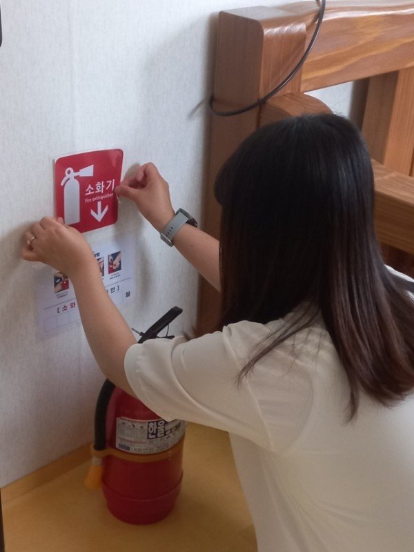 영주-5-2 경로당 내 소화기 안내 표지를 부착하고 있다.jpeg